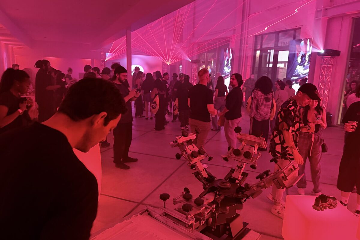 Party guests mingling under magenta lighting near live personalization equipment