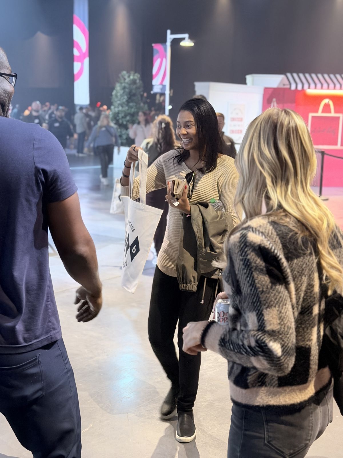 Smiling guest receiving a personalized tote bag at a brand celebration